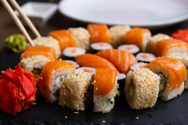 Kara tahtada nefis taze suşi rulosu. Pilavlı suşi, kremalı peynir, kırmızı balık, somon. Suşi menüsü. Japon mutfağı, restoran. Deniz ürünleri, Asya yemekleri.