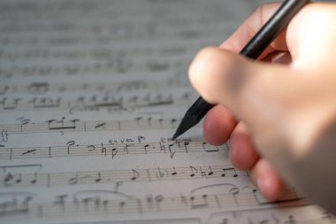 Bir müzisyenin ya da bestecinin elleri bir parça müzik yazar. Konservatuar, müzik, besteci, notalar, dersler, sanatsal yaşam konsepti. Müzik notaları ve kalemle birlikte. Yaklaş, yüzeysel alan derinliği