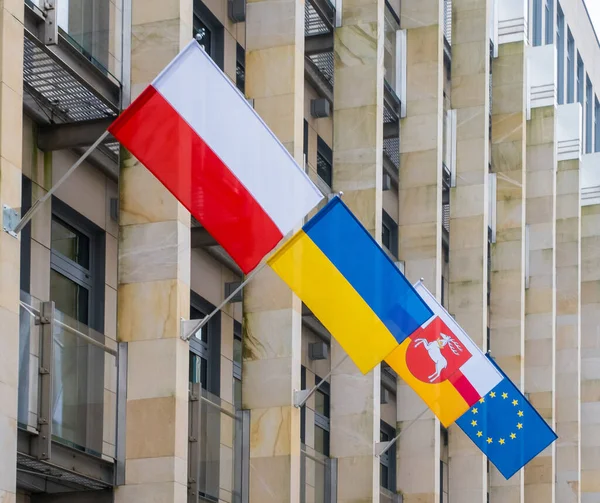 The Flags of the Poland, Ukraine, Lublin Voivodeship and European Union on the office business building background. Its a symbol of opposition to Russian aggression, a sign of solidarity and help Ukraine