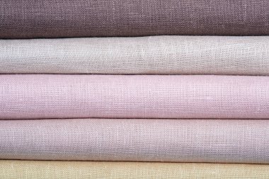 Renkli pastel kumaş yığını, yakın plan. Çarşaf arka planı. Kumaş şeritleri