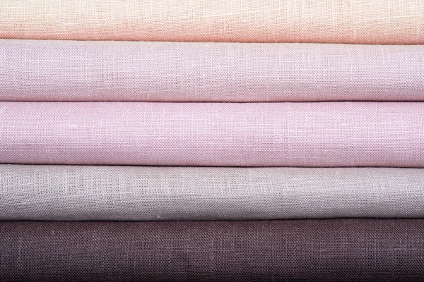 A stack of colored pastel linen fabric, close-up. Linen background. Strips of fabric