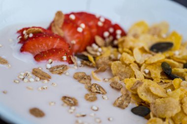 Taze dilimlenmiş çilekli yoğurt kasesi ve kuru mısır gevreği. Geleneksel mısır gevreği kahvaltı kavramı. Sağlıklı beslenme konsepti. Gıda ve sağlık