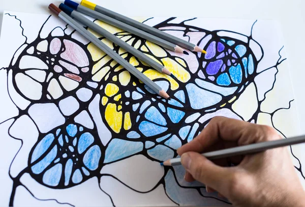 A woman draws a neurographic drawing on paper with color pencils. Neurographic art is an easy way to work with the subconscious mind through drawing. Taking care of yourself