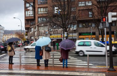 Bilbao, Bask ülkesi, İspanya - 25 Ocak 2019: İnsanlar yağmurlu bir şehir caddesinde yol ayrımında bekliyorlar. Islak hava