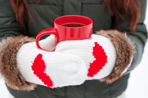 Hands in mittens with hearts holding cup — Stock Photo, Image