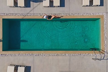 Lüks bir villa veya otelde, havuzun kenarında güneşlenen bir kadın. Hava aracı görünümü