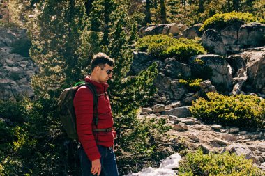 Young man hiking outdoors in the mountains. Springtime.