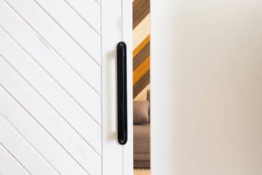 Beyaz tahta sürgülü kapı ile arka planda yer olan duvar arasında küçük bir boşluk var.