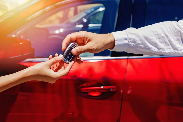 Men taking keys from the car from the hand of salesperson or car rental worker. Buying or renting a car