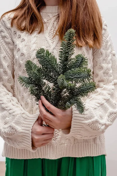 一个穿着针织毛衣的难以辨认的女人拿着一束圣诞云杉树枝特写 — 图库照片