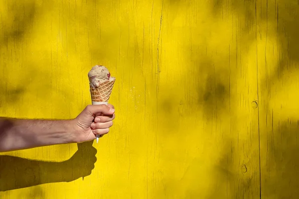 Ręka Mężczyzny Trzymająca Lody Stożku Nad Jasnożółtą Ścianą Słoneczny Letni — Zdjęcie stockowe