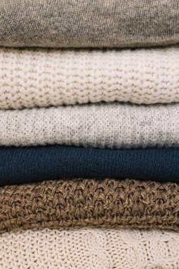 Pile of warm cozy woolen sweaters close-up. Winter apparel, textile background
