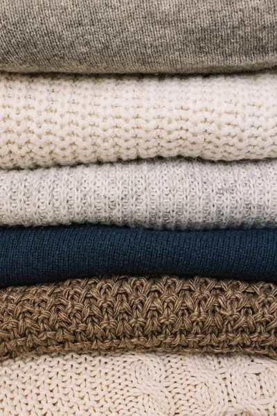 Pile of warm cozy woolen sweaters close-up. Winter apparel, textile background