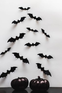 Black pumpkins and bat silhouettes on the white wall. Minimalist Halloween decor