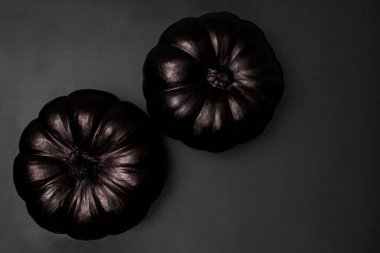 Two black pumpkins on black background, stylish Halloween decor, top view