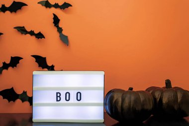 Lightbox with text Boo , black pumpkins and bat silhouettes. Halloween party decor