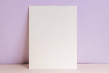 Blank card or poster mock-up over pastel purple wall, template with place for text