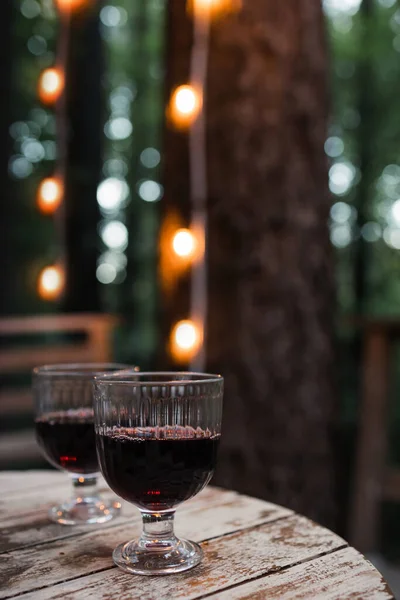 Two Glasses Red Wine Standing Wooden Table Blurred Trees Lights — 图库照片
