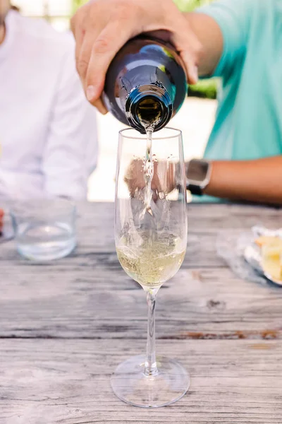 在杯子里倒入闪光的葡萄酒或香槟的男人的手的特写 暑期派对 — 图库照片