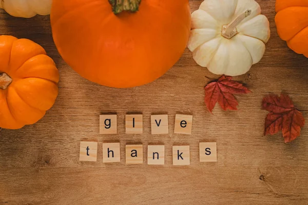 Thanksgiving flat lay composition. Pumpkins, leaves and text Give Thanks arranged from the wooden letters