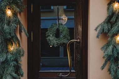 Giriş kapısı köknar çelenk ve dallarla süslenmiş. Sokaklarda Noel tatili dekoru