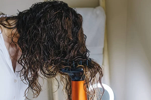 Woman diffusing her hair with dryer. Drying hair according to curly method for hair styling