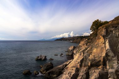 Beyaz bulutların altında mavi gökyüzü ve deniz
