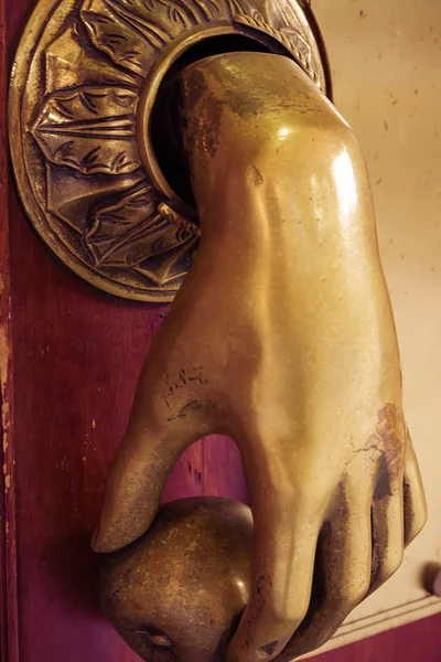 Bronze hand  entry bell to ring in wooden door — Stock Photo, Image