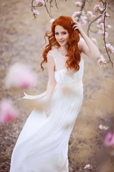 Beautiful young woman under the flowering tree — Stock Photo, Image