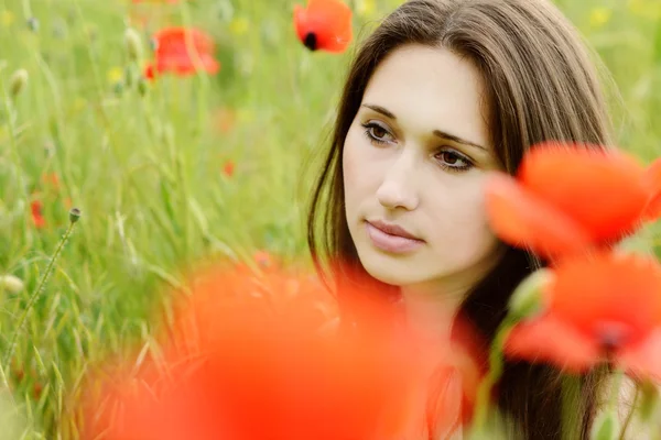 Pensive girl in poppies field — Stockfoto