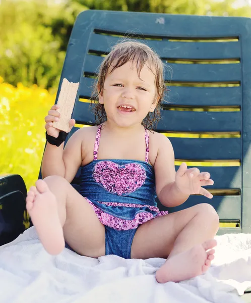 Toddler girl sitting on sun lounger — Stock Photo, Image