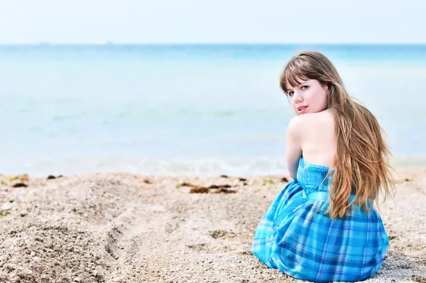 Женщина, сидящая одна на пляже — стоковое фото