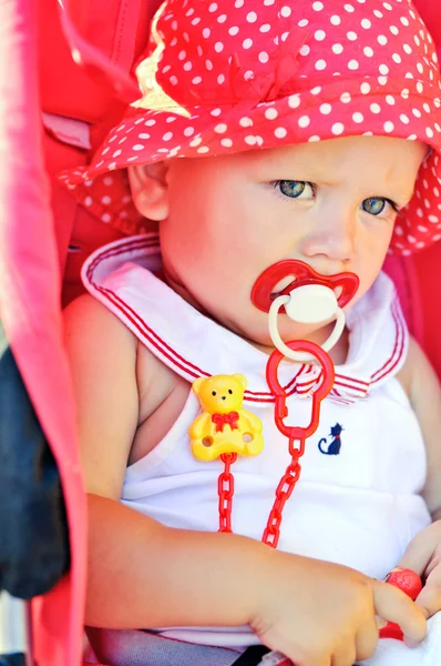 Baby girl sitting in red stroller — Stock Photo, Image