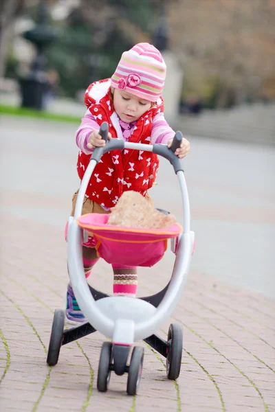 Babymeisje met speelgoed wandelwagen — Stockfoto
