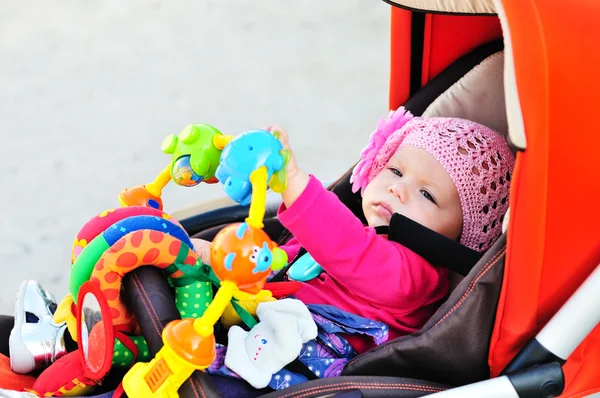 Ребёнок в коляске с игрушками — стоковое фото