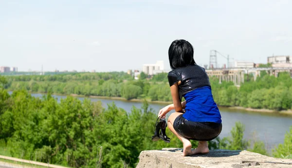 Young woman sitting on top of a stone — Stock Photo, Image