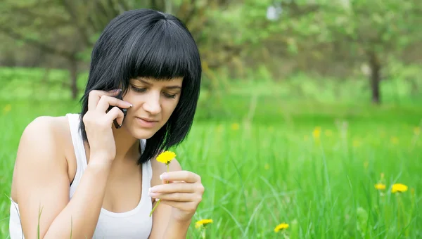 Meisje met paardebloem praten op mobiele telefoon — Stockfoto