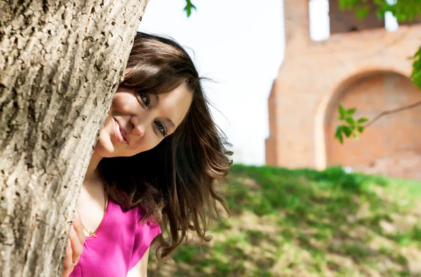 Belle jeune femme cachée derrière un arbre — Photo