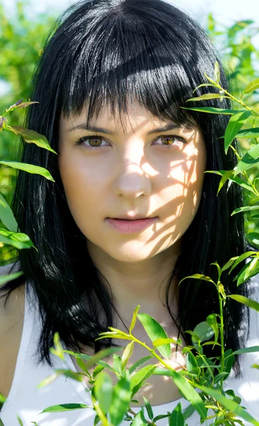 Hermosa chica en follaje verde — Foto de Stock