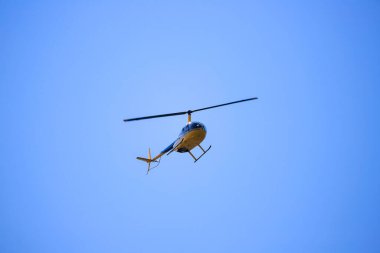 Helikopter Robinson R44 mavi gökyüzünde uçuyor