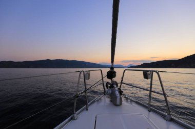 Yelkenli yatın pruvası, gün batımında yelkenliden manzara.