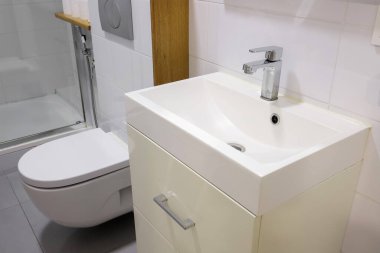 White sink with faucet and toilet bowl in the bathroom