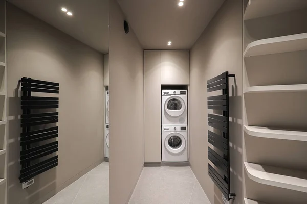 Washing machine inside empty dressing room interior with shelves and mirror