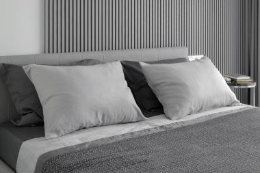 Yatak odasındaki çift kişilik yatakta gri yastıklar.