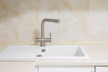 Mutfakta beyaz granitli musluk var.