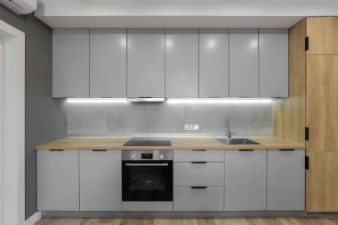 Mutfağın iç tarafındaki gri mutfak mobilyaları.