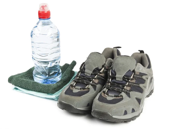 Een fles water, sportschoenen en handdoek geïsoleerd op witte achtergrond — Stockfoto