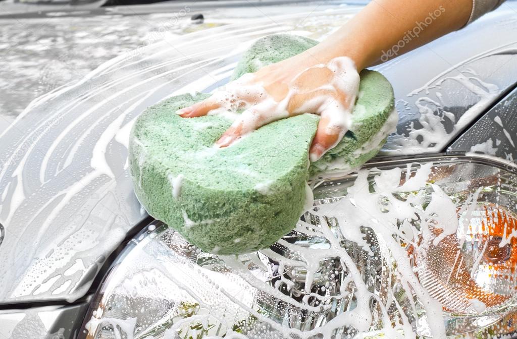 Hand with sponge cleaning car