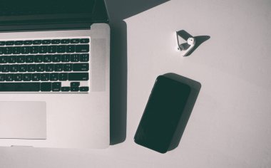 Laptop, cep telefonu ve kulaklıklar beyaz masada. 