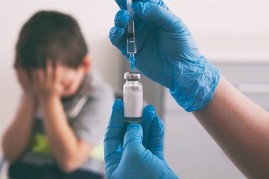 Çocuk iğneden korkuyor. Çocuk aşıdan korktuğu için elleriyle yüzünü kapadı.